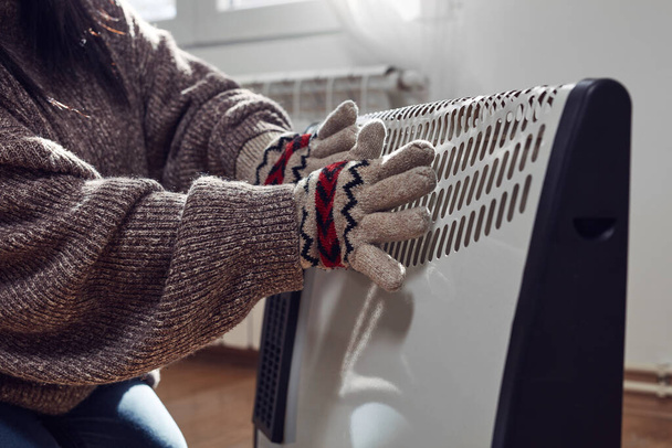 Woman in jacket, sweater and hand gloves indoors on a chilly winter day, energy and gas crisis, cold room, heating problems. - Fotografie, Obrázek