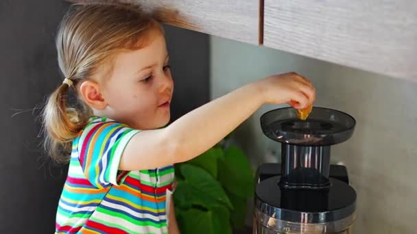 Egy kislány, aki friss gyümölcslevet főz az asztalon az otthoni konyhában. Kiváló minőségű 4k felvételek - Felvétel, videó