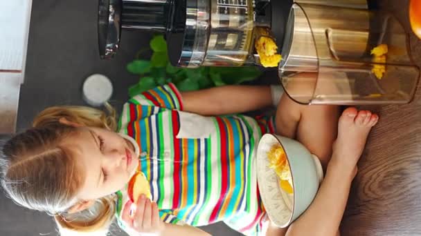 Mała dziewczynka robi świeży sok siedząc na stole w domowej kuchni. Wysokiej jakości materiał 4k - Materiał filmowy, wideo
