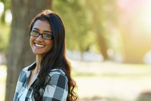Relaxed beauty. A beautiful young woman wearing glasses standing in a park - Photo, Image