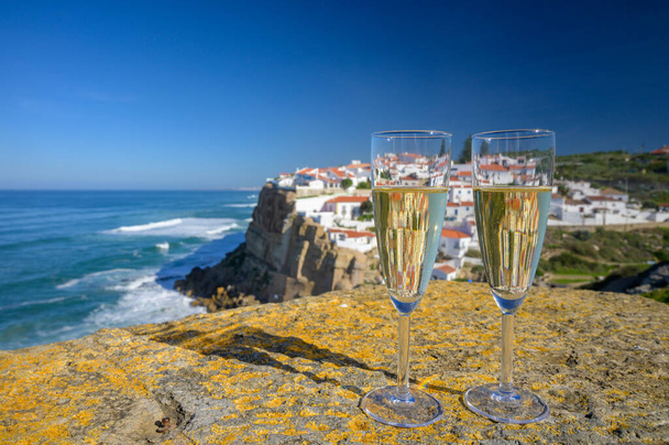 Ποτήρια σαμπάνιας λευκό αφρώδες κρασί και θέα σε λευκά σπίτια του γραφικού χωριού Azenhas do mar, περιοχή της Λισαβόνας, Πορτογαλία - Φωτογραφία, εικόνα