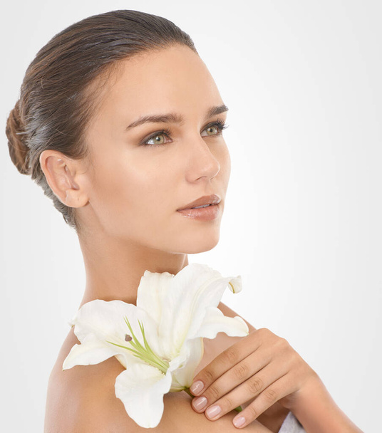 Perfecting perfection. Studio beauty shot of an attractive brunette woman holding a flower - Photo, Image