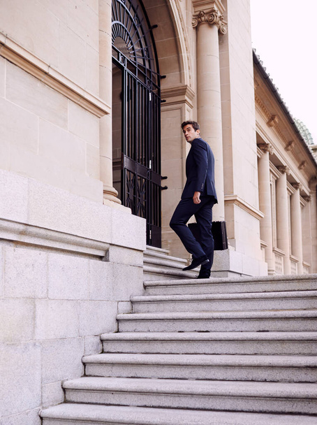 Siempre el primero en llegar a la oficina... un hombre de negocios guapo con un maletín parado fuera de un edificio de la ciudad - Foto, Imagen