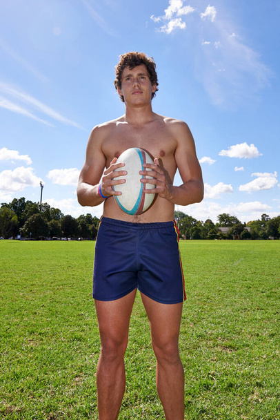 He aspires to be a great rugby player. A fit young man looking focused while standing with a rugby ball - Foto, imagen