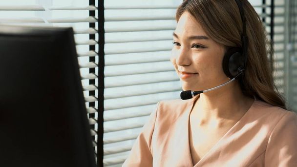 Competent female operator working on computer and while talking with clients. Concept relevant to both call centers and customer service offices. - Foto, Imagem