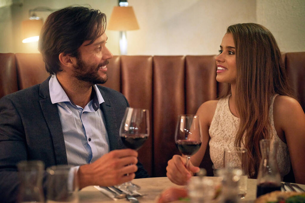 Couple, valentines day and restaurant date with wine to celebrate love and happy communication. Young man and woman together for fine dining, drinks glass and romantic dinner for celebration night. - Photo, Image