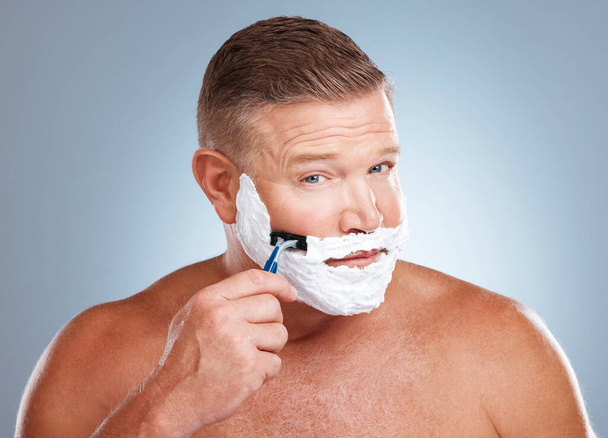Shaving cream, face and man with razor in studio isolated on a gray background for hair removal. Portrait, skincare and mature male model with facial foam to shave for aesthetics, health or wellness. - Valokuva, kuva