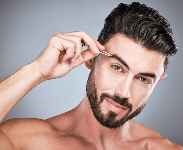 Face, eyebrow and man with tweezers in studio isolated on a gray background for wellness. Health, hair removal and portrait of male model with facial product for grooming, cleaning and epilation - Fotografie, Obrázek