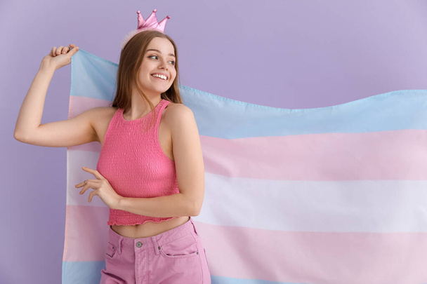 Νεαρή γυναίκα με στέμμα με σημαία τρανσέξουαλ στο λιλά φόντο - Φωτογραφία, εικόνα