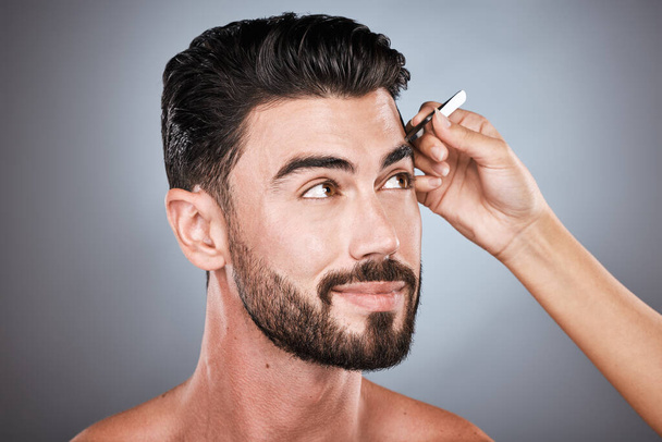 Face, barber and man with tweezers in studio isolated on a gray background for wellness. Thinking, hair removal and male model with facial product to pluck eyebrows for grooming and beauty at salon - Foto, afbeelding