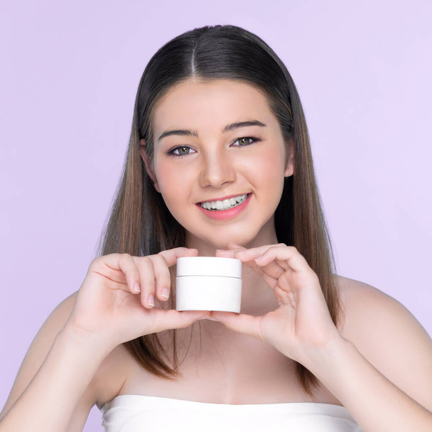 Young charming girl with natural beauty, perfect smooth skin hold lotion, cream, moisturizer jar. Beautiful girl show skincare product smiling on isolated background. - Fotografie, Obrázek