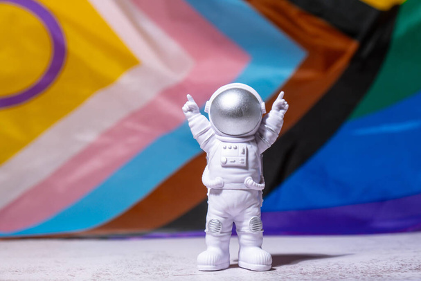 Toy astronaut on Rainbow LGBTQIA flag made from silk material background. Happy pride month. Symbol of LGBTQ pride month. Equal rights. Peace and freedom. Support LGBTQIA community. Diversity equality - Photo, Image