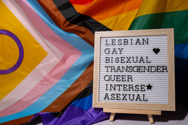 LGBTQIA description frame on Rainbow LGBTQIA flag made from silk material. LESBIAN, GAY, BISEXUAL, TRANSGENDER, QUEER, INTERSEX, ASEXUAL. Symbol of LGBTQ pride month. Equal rights. Peace and freedom. Support LGBTQIA community. Diversity equality - Foto, Imagen