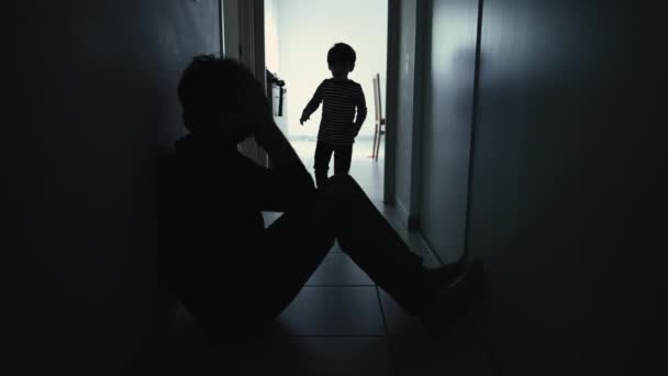Депресивний батько втішився сином, сидячи в коридорі в силуеті. Дитина обіймає сумного батька під час кризи
 - Кадри, відео