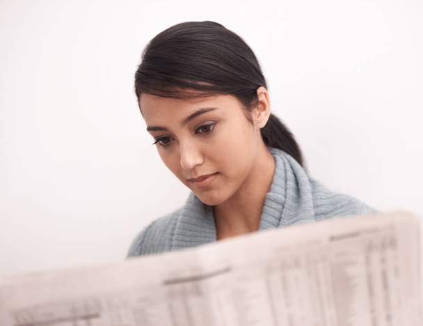 Catching up on the latest news. An attractive young woman reading a newspaper - Photo, Image