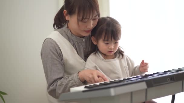Parents and children practicing playing the piano - Filmmaterial, Video