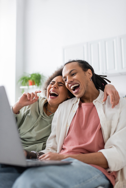 アフリカ系アメリカ人のカップルを笑いながらコメディ映画をラップトップでホーム  - 写真・画像