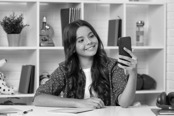 happy kid making selfie in classroom. september 1. child making video blog. blogging on phone. vlogger with cellphone. young influencer. teen girl blogger use smartphone. back to school. - Fotoğraf, Görsel