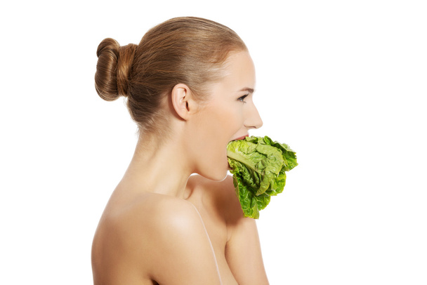 Side view of nude woman eating lettuce - Foto, Imagen