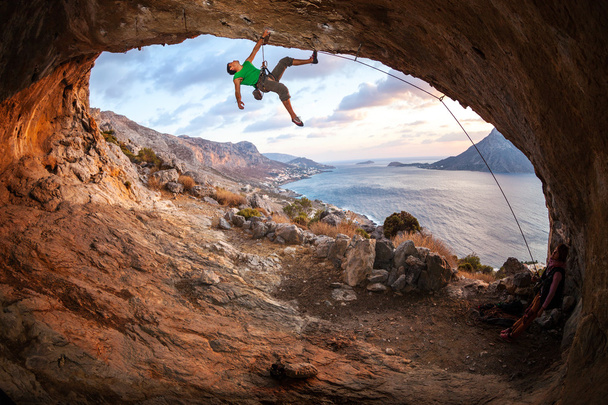 Hombre escalador escalando a lo largo de un techo en una cueva al atardecer. Isla de Kalymnos, Grecia
 - Foto, imagen