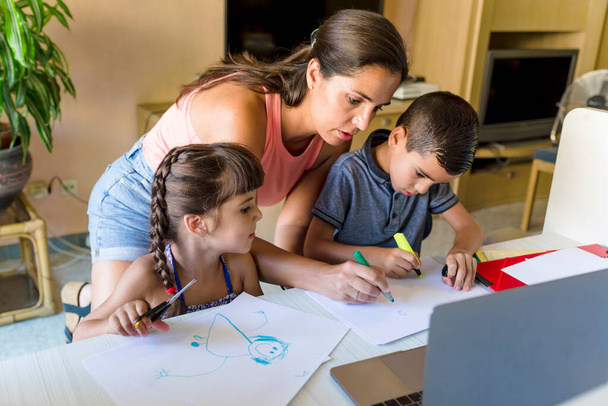 Crianças irmã e irmão fazendo lição de casa e desenho em conjunto com a jovem mãe em casa - Foto, Imagem