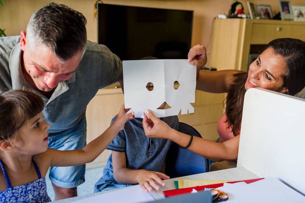Діти сестра і брат роблять домашнє завдання і малюють разом з молодими батьками вдома
 - Фото, зображення
