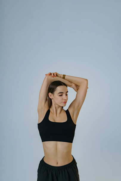 Sporty woman doing warm-up before training session in gym on studio background. High quality photo - Zdjęcie, obraz