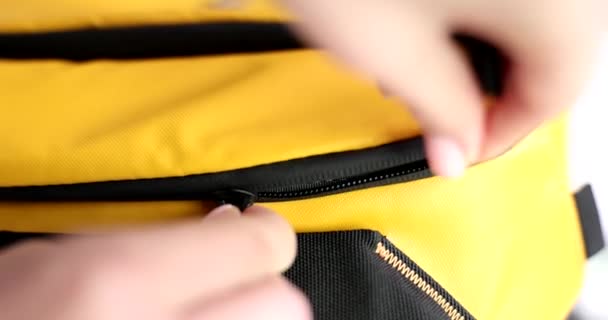 Hand closes yellow sack backpack. Closeup of a hand closes a padlock travel safety and theft - Video, Çekim