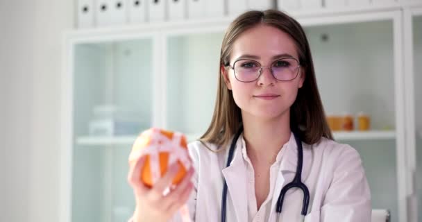 Διατροφολόγος κατέχει πορτοκάλι ή μανταρίνι φρούτα και ταινία μέτρησης στο χέρι. Γιατρός συμβουλές για να τρώνε υγιεινά τρόφιμα με βιταμίνες - Πλάνα, βίντεο