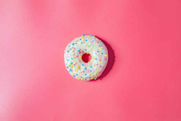 Donuts with icing on pastel pink background. Sweet donuts. top view assorted with various chocolate glazed and sprinkles, sugar sweets concept candy - Φωτογραφία, εικόνα