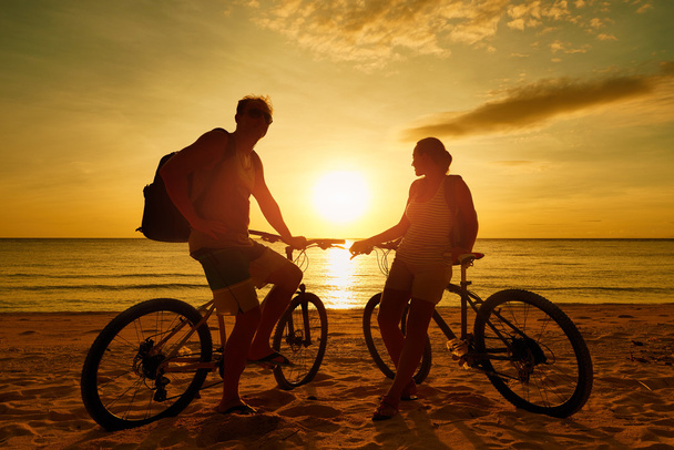 Bisiklet izlerken gün batımı ile çift turist. Siluet insanlar - Fotoğraf, Görsel