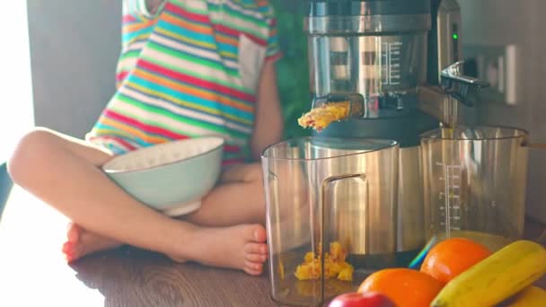 Little girl making fresh juice on the table in home kitchen. Focus on juicer. High quality 4k footage - Imágenes, Vídeo