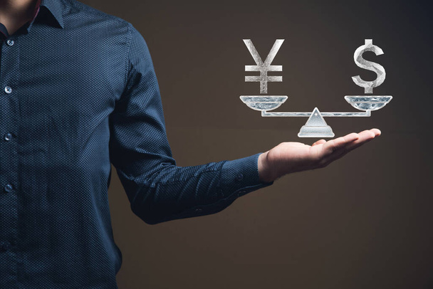 Dollar and yen on scales from the net. Man holding in his hand - Photo, image