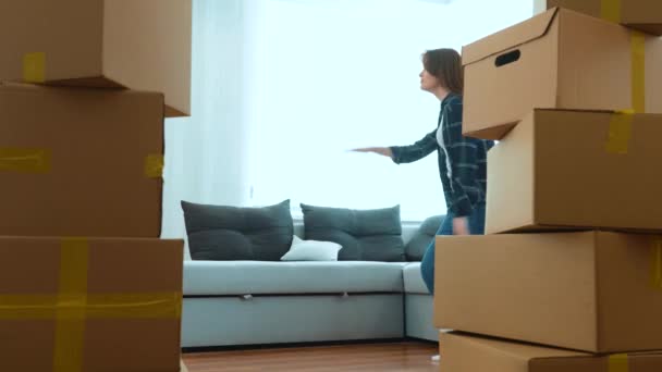 Happy positive couple of man and woman having fun dancing in room in new home between cardboard boxes. Caucasian young wife and husband doing funny dance in new apartment. Moving day. Real time - Filmagem, Vídeo