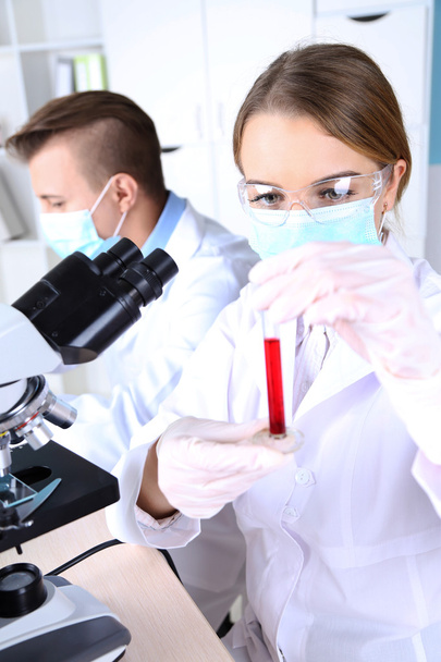 Científicas jóvenes y masculinas con microscopio en laboratorio
 - Foto, Imagen