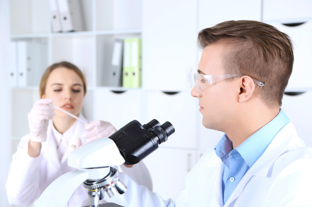 Giovani scienziati di sesso femminile e maschile con microscopio in laboratorio
 - Foto, immagini