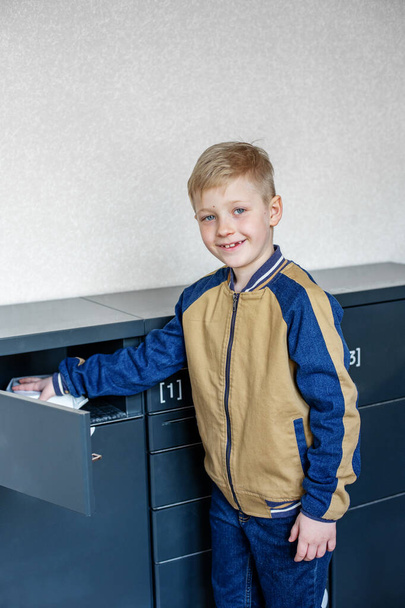 Концепция доставки почты и онлайн-покупки. Мальчик клиент с помощью автоматического самообслуживания после терминала или шкафчика - Фото, изображение
