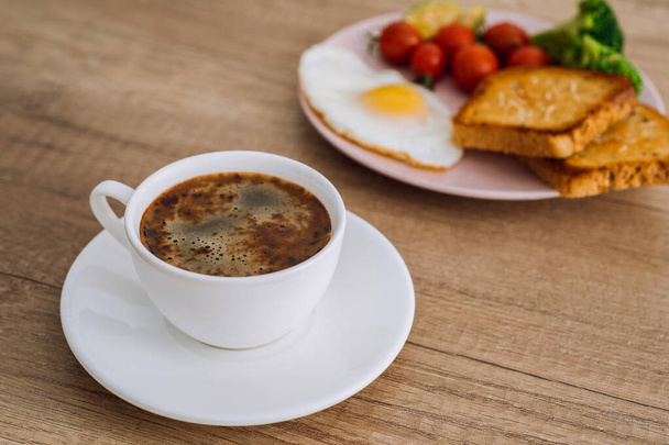 Κοντινό φλιτζάνι καφέ σκέτο με σπιτικό πρωινό σε ξύλινο τραπέζι - Φωτογραφία, εικόνα