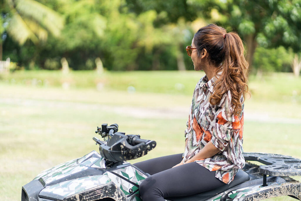 This dynamic image features a young, fashionable woman who effortlessly balances style and adventure as she rides an ATV. The pose she strikes is confident and daring - Foto, Imagem