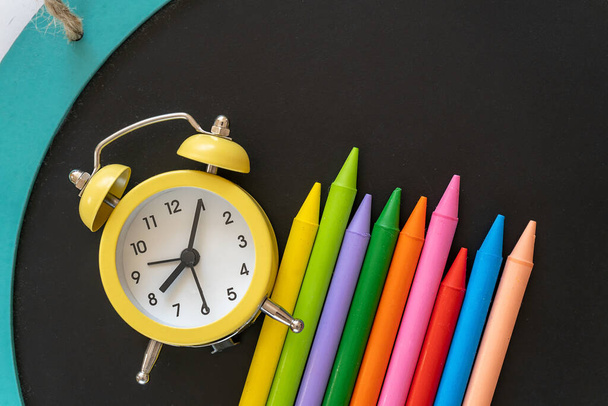 黄色のクロック、テーブルの上の学校の黒板に鉛筆。学校に戻り、子供のための創造的な研究、教育、数学。平置き - 写真・画像