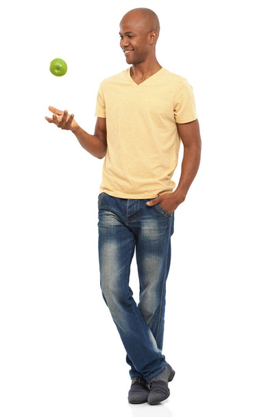 Guapo y saludable. Una toma de cuerpo entero de un guapo afroamericano lanzando una manzana al aire - Foto, imagen