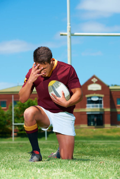 C'est un sport d'hommes. Plan complet d'un jeune rugby agenouillé sur le sol tout en couvrant ses yeux - Photo, image