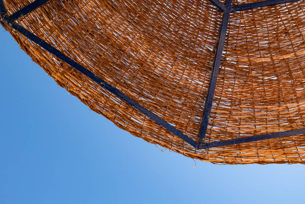 Travel and vacation concept. A fragment  of a reed sunshade against a clear, blue sky. Red Sea, Egypt - Photo, Image