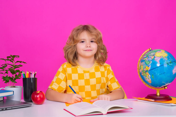 Kid boy from elementary school with book. Smart caucasian school boy kid pupil going to school. School child isolated on red pink studio background. Concept of education and learning - Photo, Image
