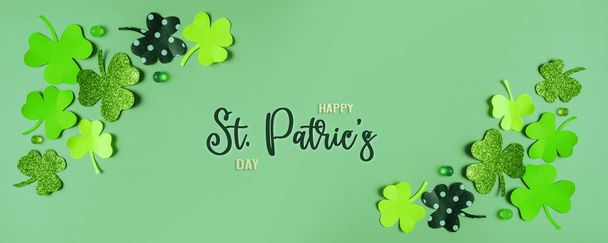 Happy St. Patrick's Day greeting text. Paper clover leaves on colored background banner format. - 写真・画像