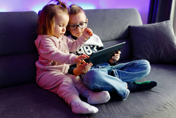 Danyas hermano mayor le enseña a su hermana menor cómo utilizar una tableta. Los niños juegan con gadgets. - Foto, Imagen