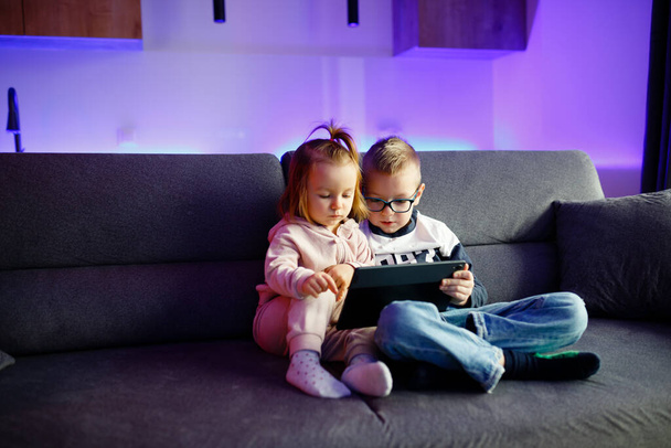Danyas irmão mais velho ensina sua irmã mais nova como usar um tablet. Crianças brincam com gadgets. - Foto, Imagem