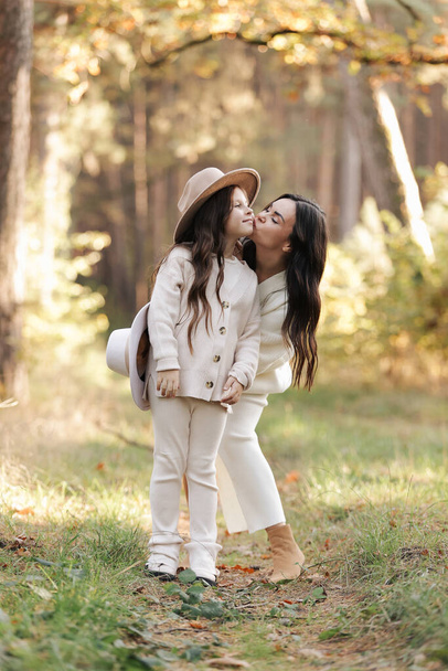Mothers day. Beautiful smiling young mom with teen daughter are hugging and looking at camera outdoors in the autumn park. Family day. Idyllic stylish family of two communicate alone. happy childhood - Valokuva, kuva