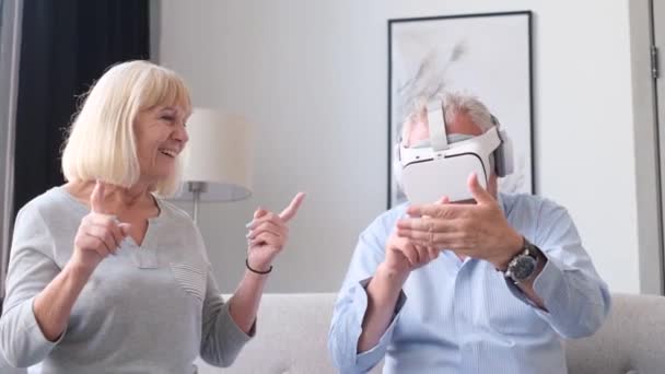 Happy grandparents are relaxing sitting on the sofa, they are using virtual reality glasses. Happy life in retirement - Footage, Video