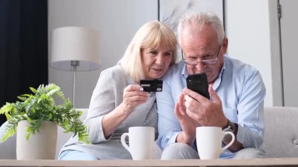 Dziadkowie dokonują zakupu online za pomocą smartfona i karty kredytowej. Współcześni starzy ludzie używają gadżetów. 4k wideo - Materiał filmowy, wideo